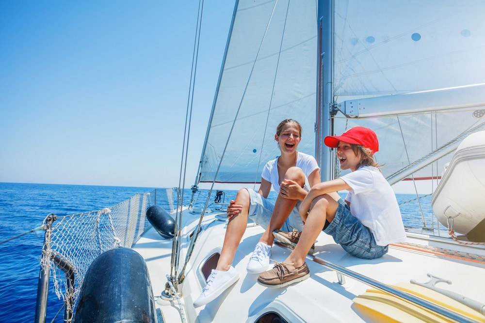 Boy with his sister on board of sailing yacht on summer cruise